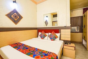 A hotel room with a bed, a nightstand, a mirror, and a wardrobe. - Hotel Lalbagh Gardenia (Bengaluru)