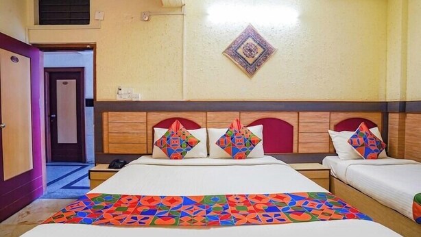 A hotel room with a large bed, two bedside tables, and a headboard with decorative elements. - Hotel Lalbagh Gardenia (Bengaluru)