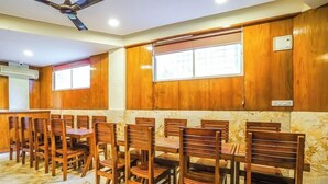 A dining area with wooden panel walls, a ceiling fan, and a tiled floor. - Hotel Lalbagh Gardenia (Bengaluru)