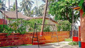 Un espace patio avec une balançoire, un mur en briques et une vue sur une maison avec un toit en tuiles.