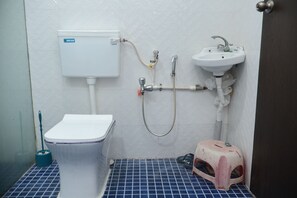 A small bathroom with a toilet, sink, and shower. - Sam's Outhouse Stay (Mumbai)