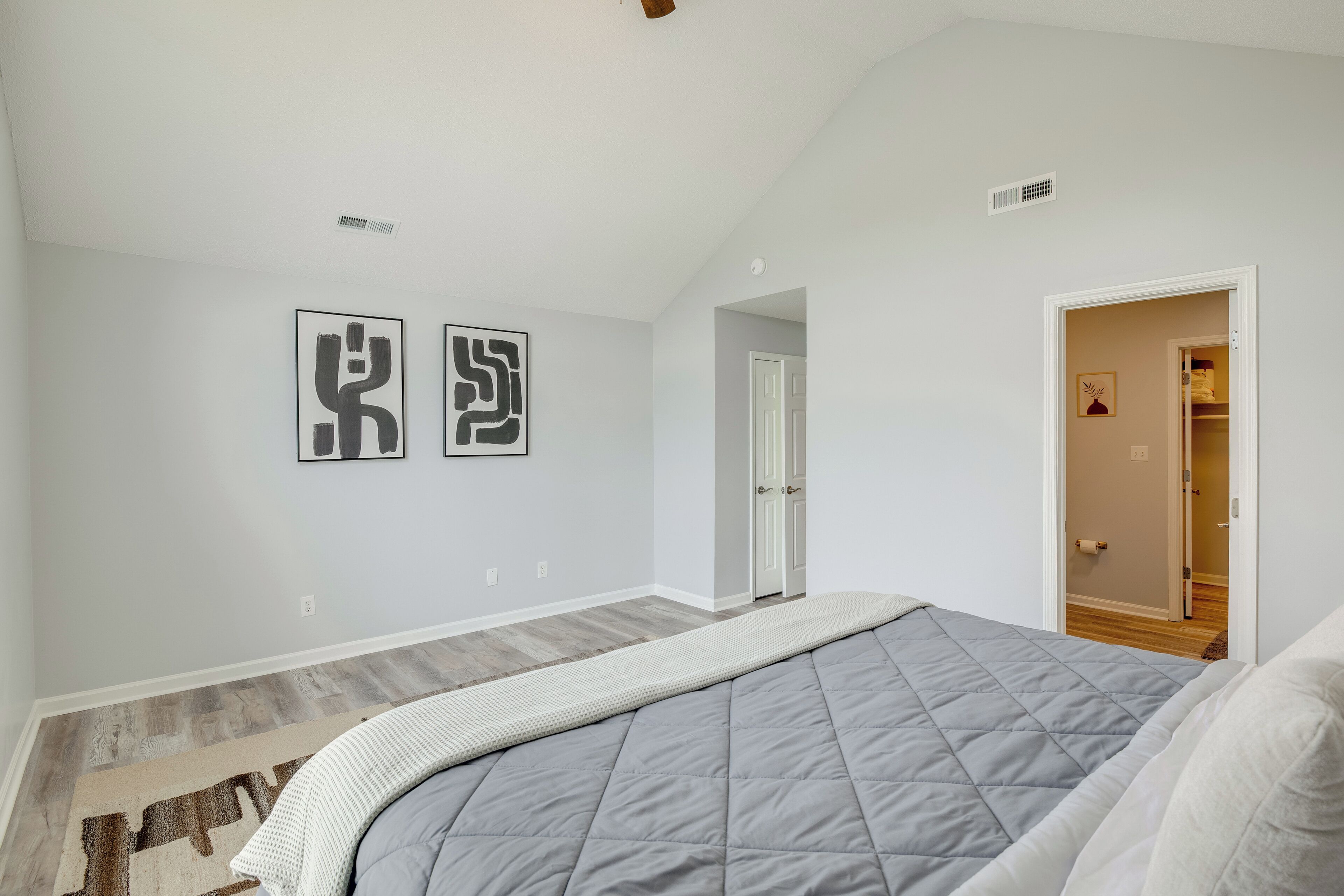 Une chambre à coucher avec un lit, un tapis et deux œuvres d’art murales.