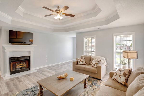 A living room with a fireplace, a sofa, a coffee table, and a ceiling fan. - Patio & Spacious Yard: Home in Athens (Athens)