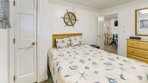 A bedroom with a bed, a wooden headboard, a wall-mounted ship's wheel, a dresser, and a mirror. - Walk to Ocean & Pier: Prime OOB Condo! (Old Orchard Beach)