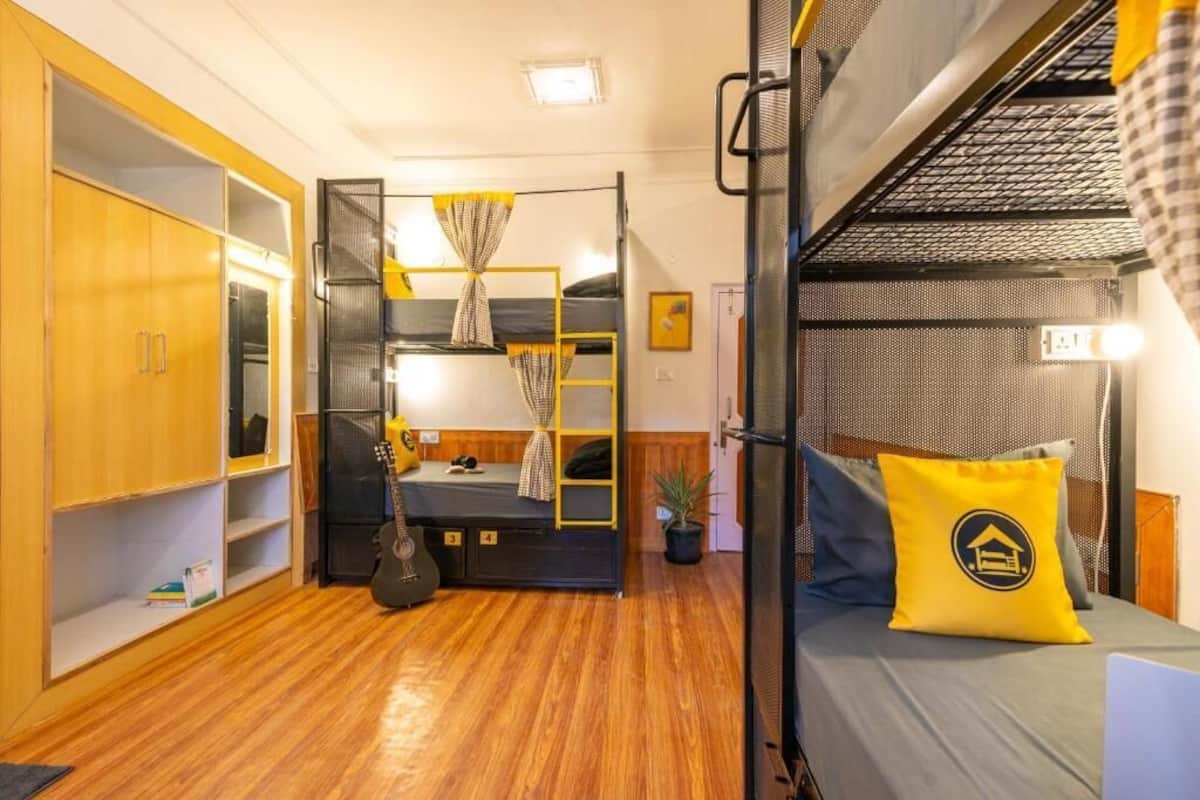 A compact room with bunk beds, a wardrobe, and a small desk area.