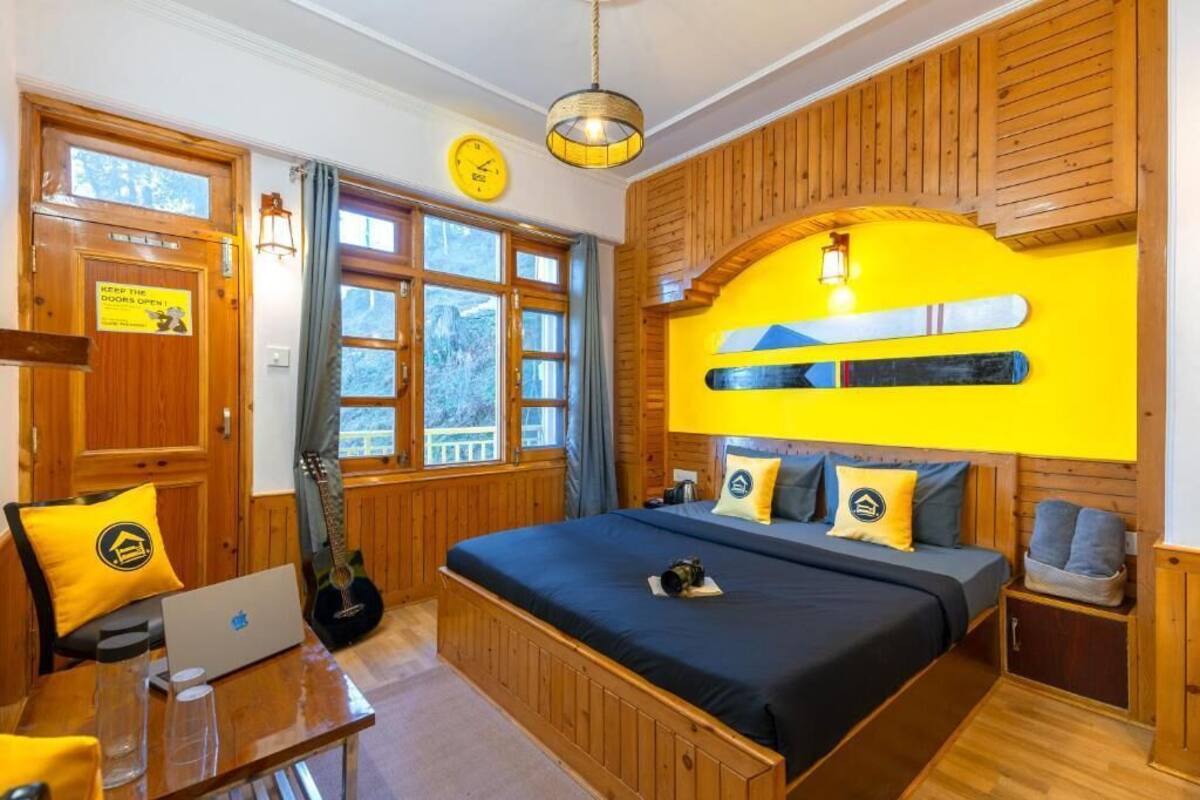 A wooden room with a bed, a desk, and a guitar.
