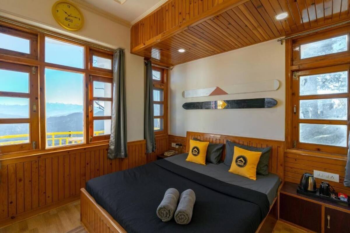 A wooden-paneled room with a bed, a clock, and a ski lift image on the wall.