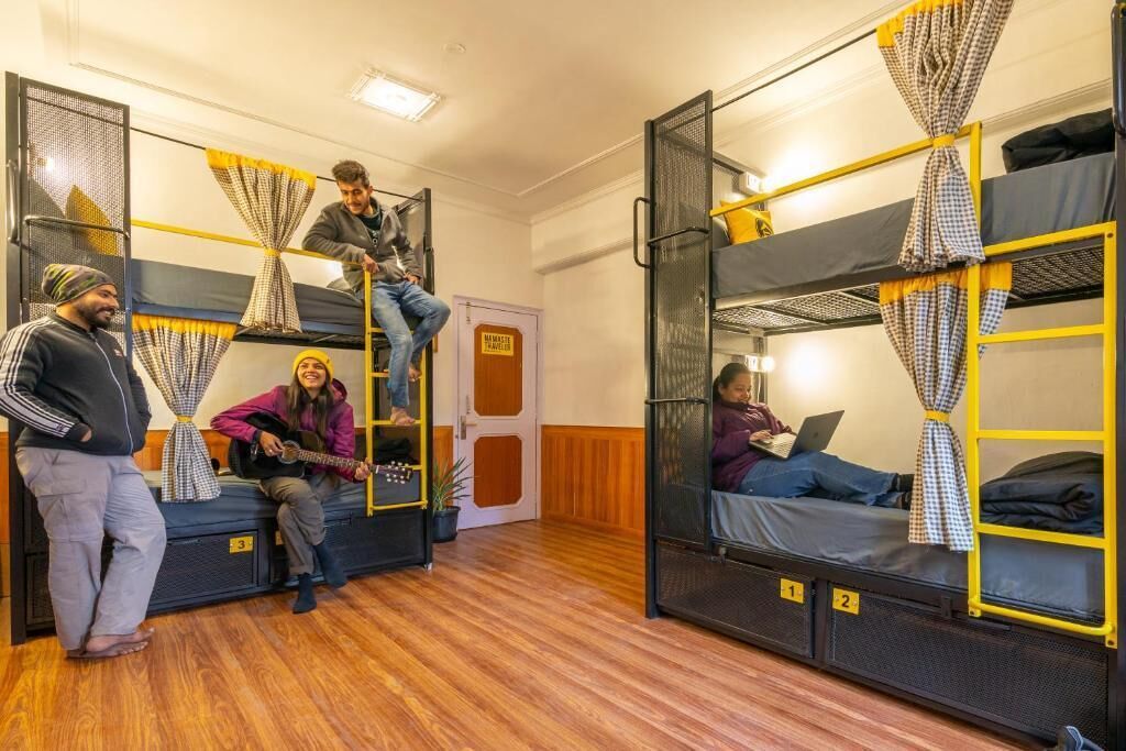 A dormitory room with bunk beds, a door with a sign, and a wooden floor.