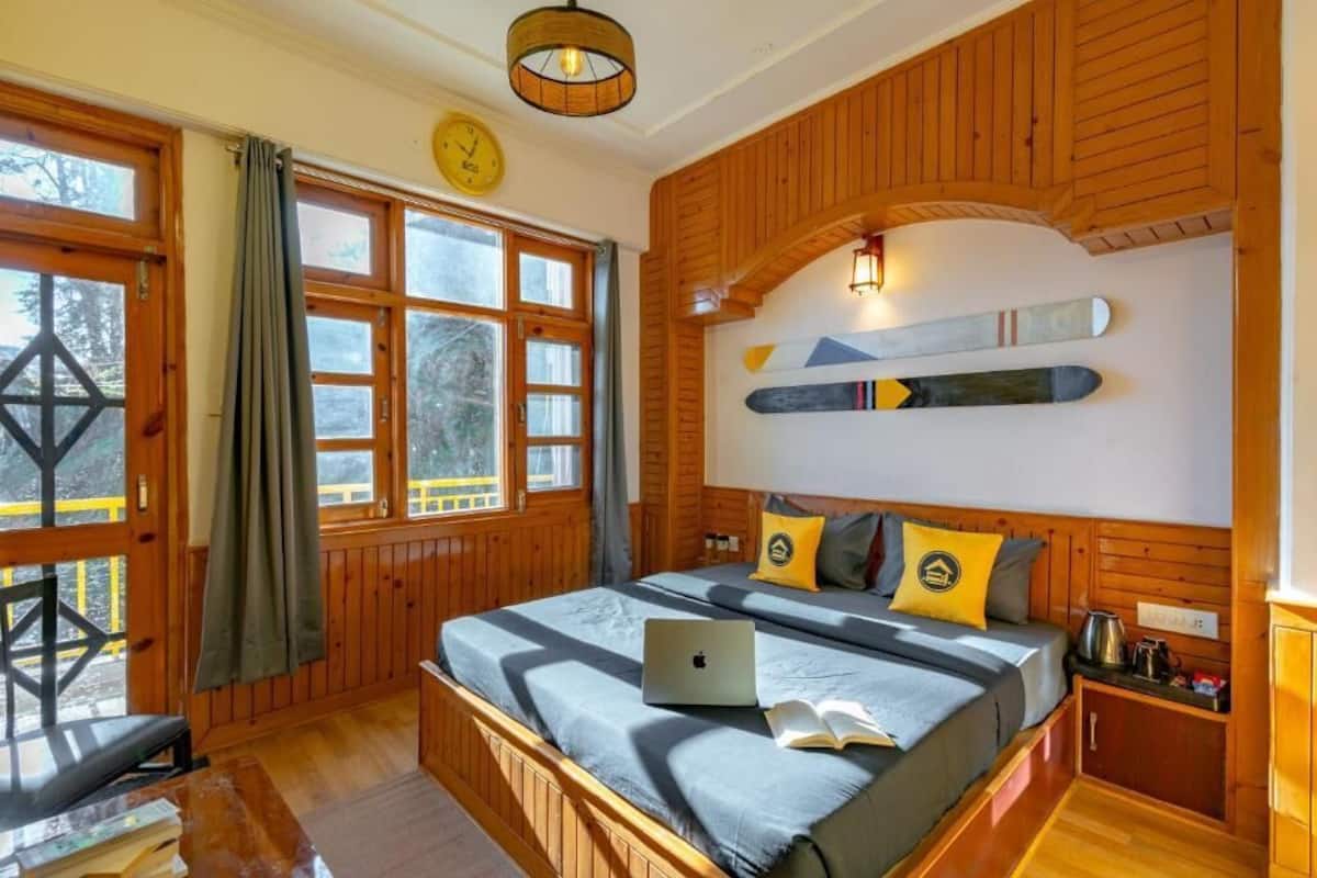 A wooden cabin bedroom with a bed, a laptop, and a ski board on the wall.