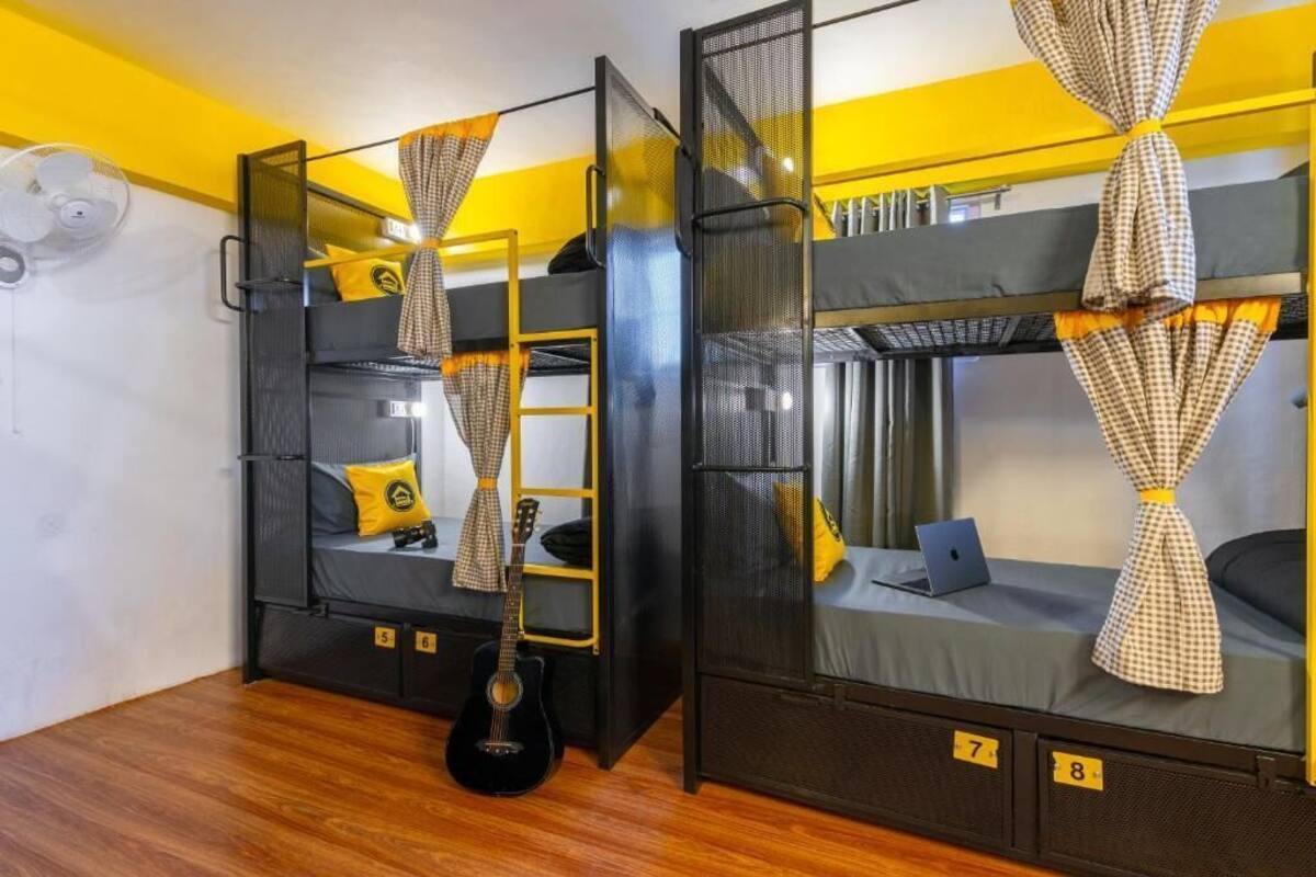 A room with bunk beds, a ladder, a guitar, and a fan.