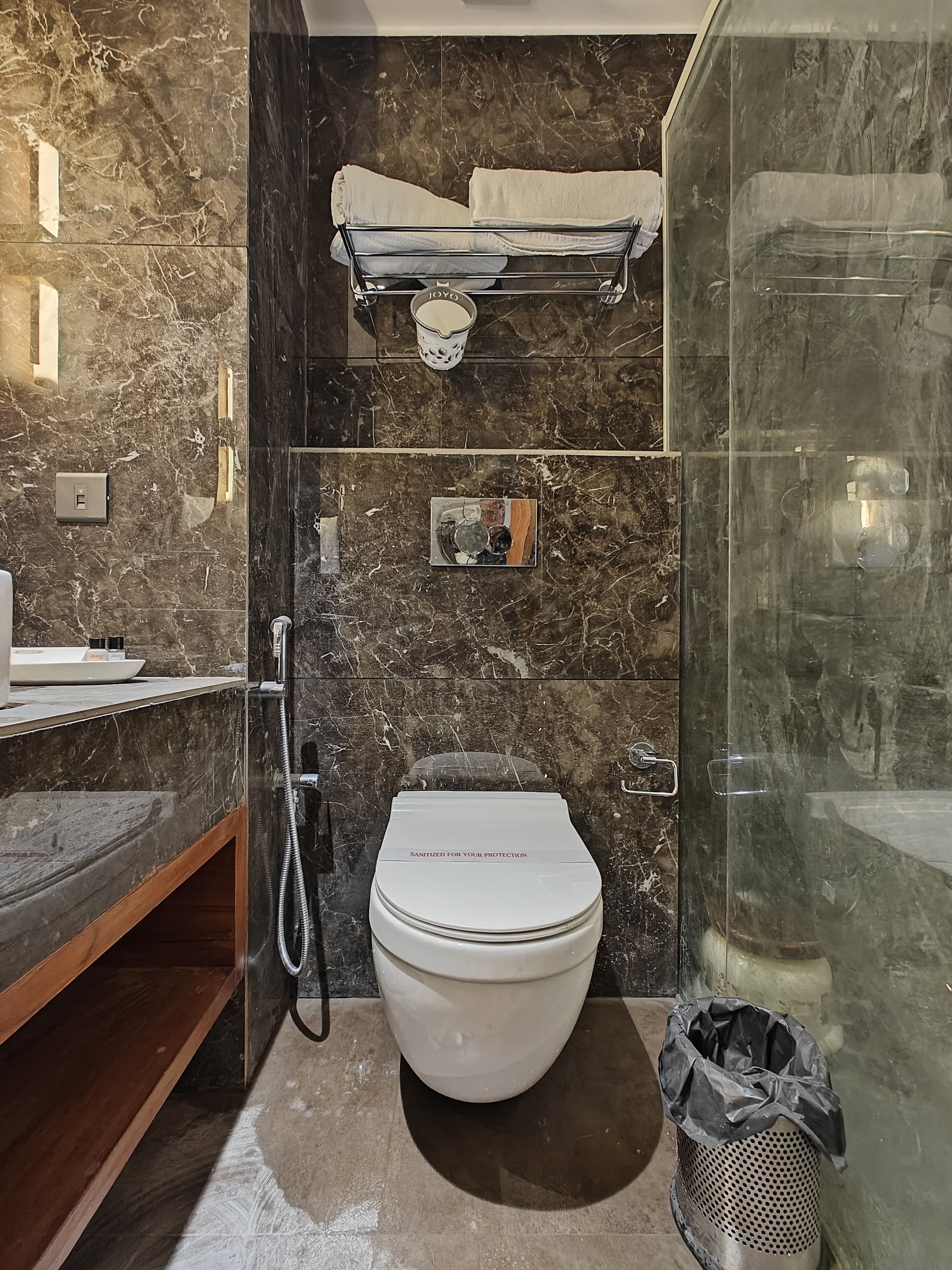 Un baño moderno con salpicadero de mármol, inodoro, cabina de ducha y un perchero para toallas.