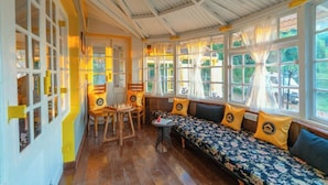 A cozy room with a wooden bench, a small table, and a chair. - The Hosteller Ooty (Ootacamund)