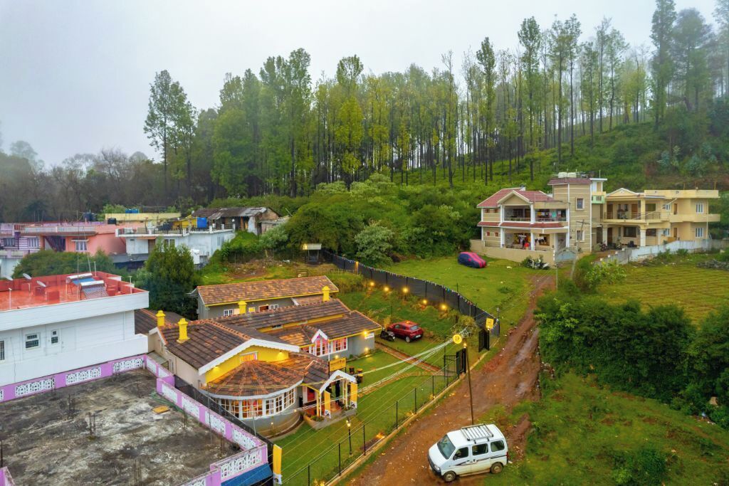 A residential area with houses, a dirt road, and a white van parked near a house with a red car.