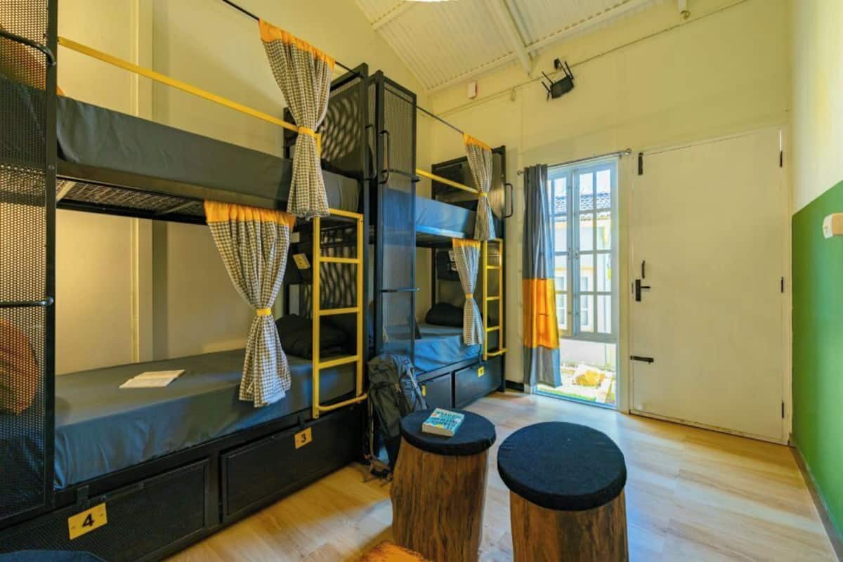 Ein Schlafsaalzimmer mit Etagenbetten, einem kleinen Tisch und einer Tür zu einem Außenbereich.
