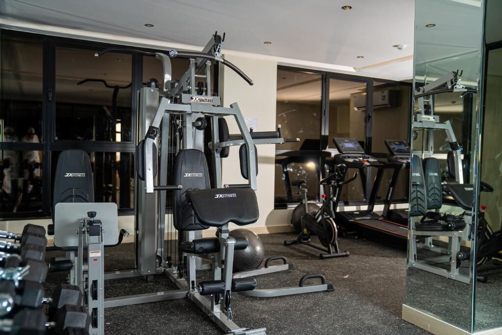 A gym with various exercise equipment, including a bench press, dumbbells, and treadmills.