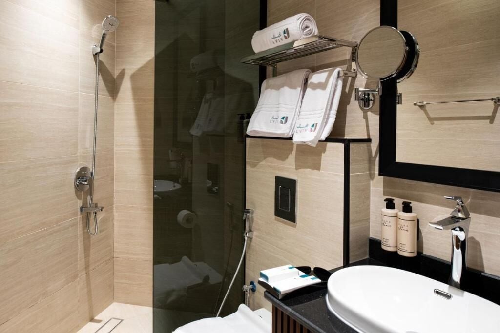 A modern bathroom with a glass-enclosed shower, a vanity with a sink, and a mirror.