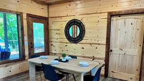 A wooden interior with a dining table set for four, surrounded by chairs. - RiverBend Haven-Sleeps 8-River Access (Broken Bow)