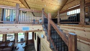 A wooden cabin with a loft bedroom, a dining area, and a staircase. - RiverBend Haven-Sleeps 8-River Access (Broken Bow)
