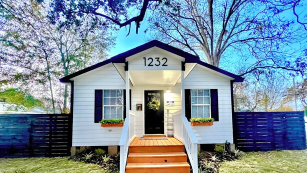 Una casa pequeña de un solo piso con el número '1232' sobre la puerta principal.