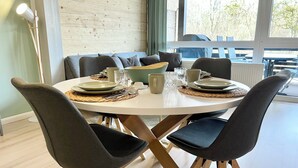 Un coin repas avec une table ronde dressée pour quatre personnes, entourée de chaises à l’assise rembourrée et de couleur sombre.