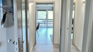 Un couloir avec une porte vitrée donnant sur une pièce d’où l’on peut admirer un parc.