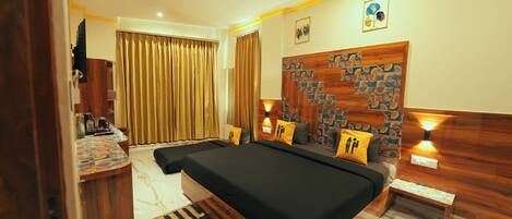 A hotel room with a large bed, a desk with a chair, a small table, and a ceiling fan.