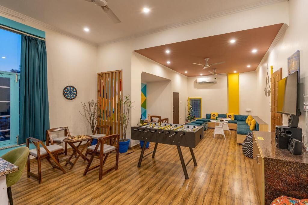 A spacious living room with a foosball table, a dartboard, and a sofa set.