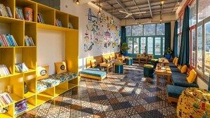 A cozy reading area with yellow bookshelves, comfortable seating, and a colorful tiled floor. - The Hosteller Rishikesh, Upper Tapovan (Uttarakhand)