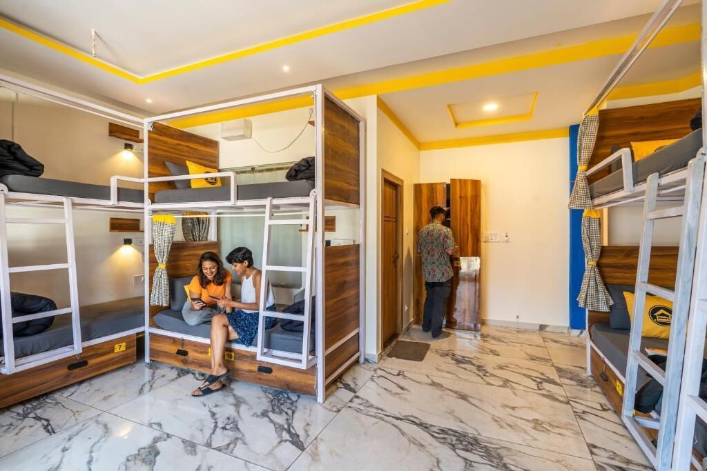 A room with bunk beds, a seating area, and a person standing by a door.