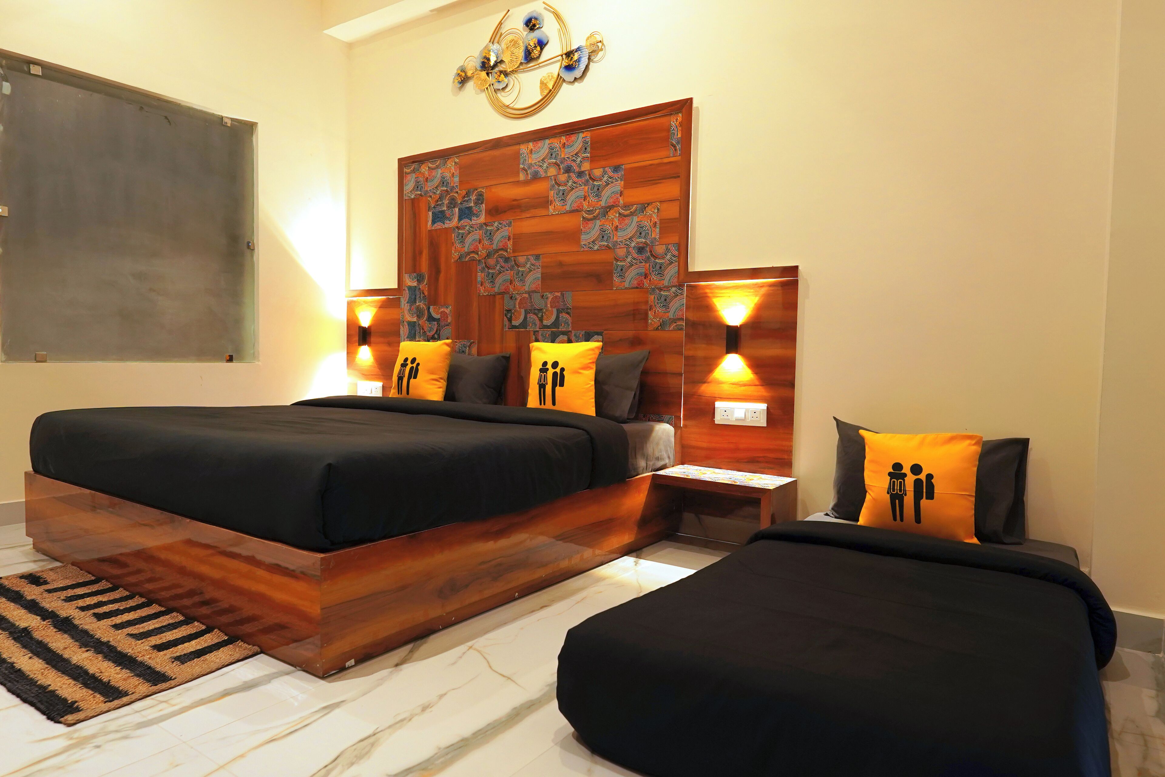 Une chambre moderne avec une tête de lit en bois, deux lits et des appliques murales décoratives.