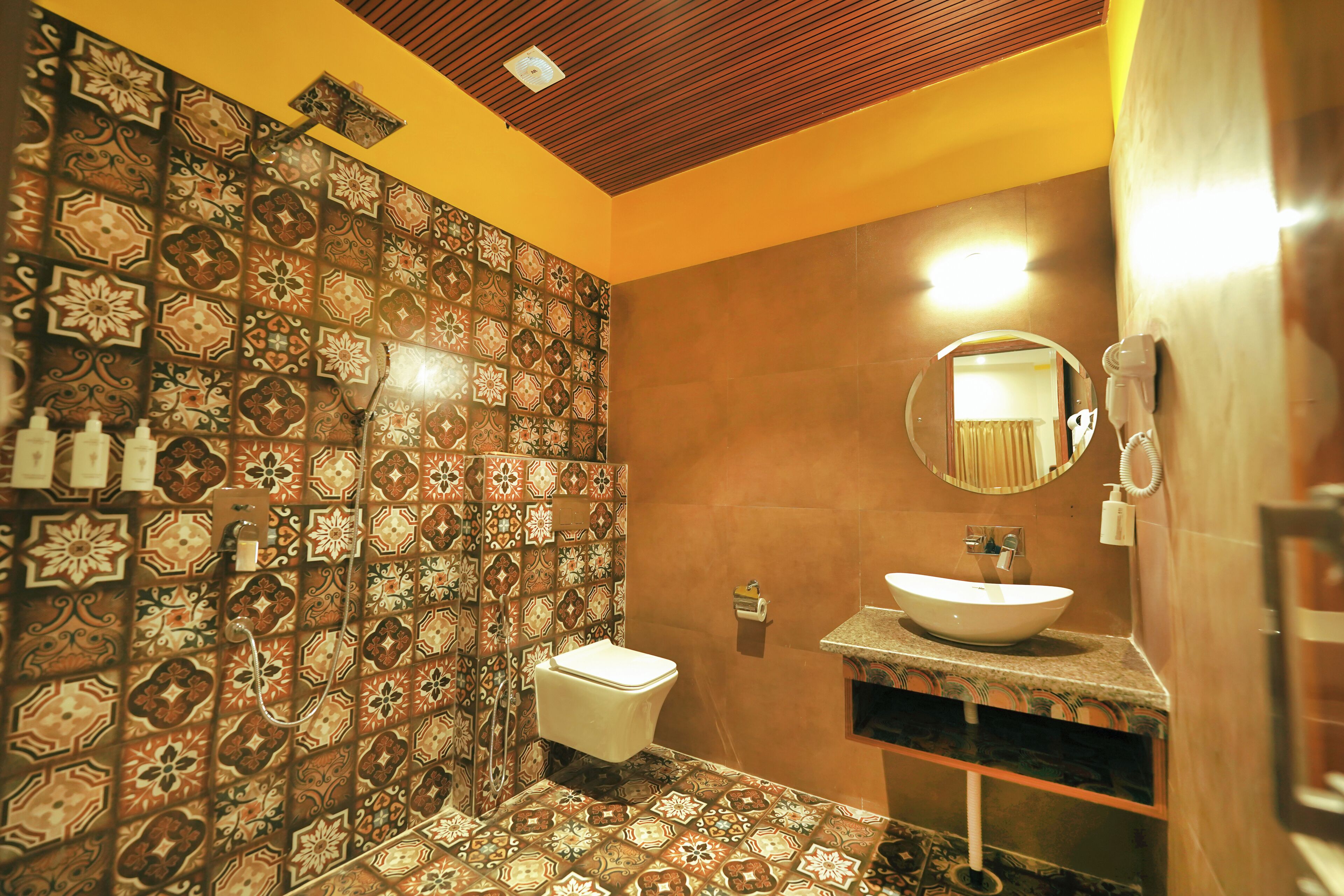 Un baño con pared de azulejos, un lavabo, un espejo y un inodoro.