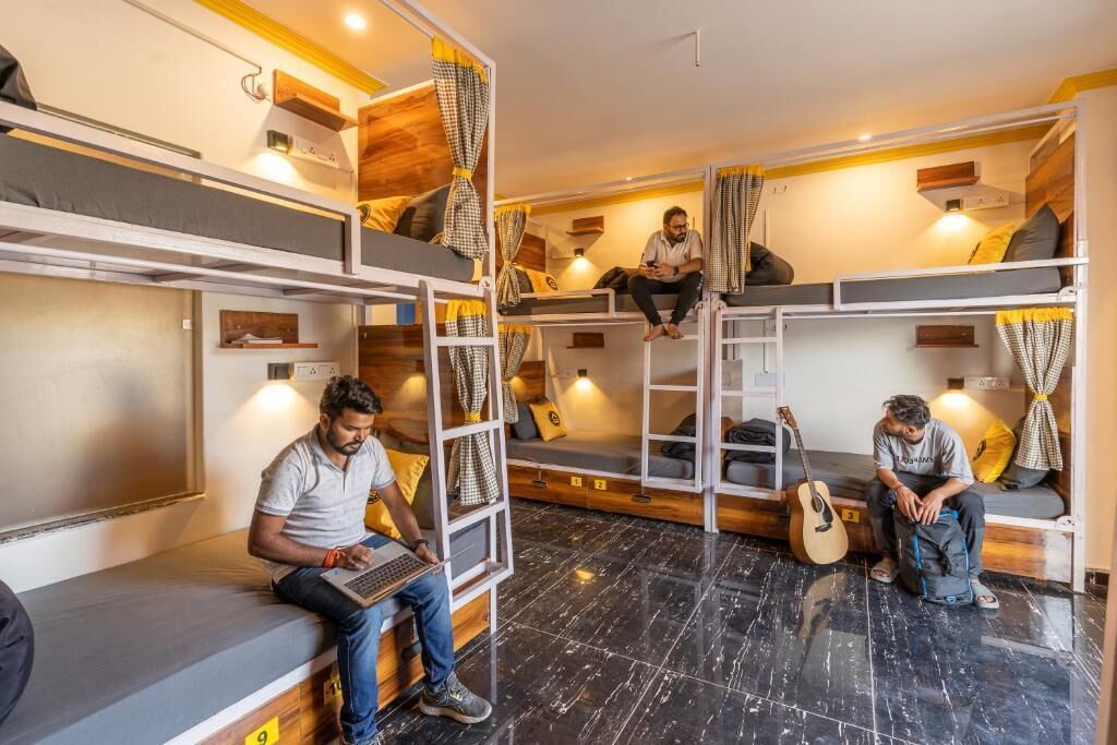 A dormitory-style room with bunk beds, a laptop, and a guitar.
