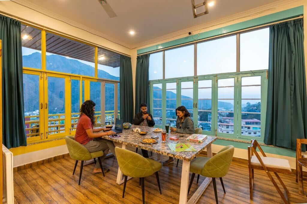 A dining area with a table set for four, large windows with curtains, and a view of mountains.