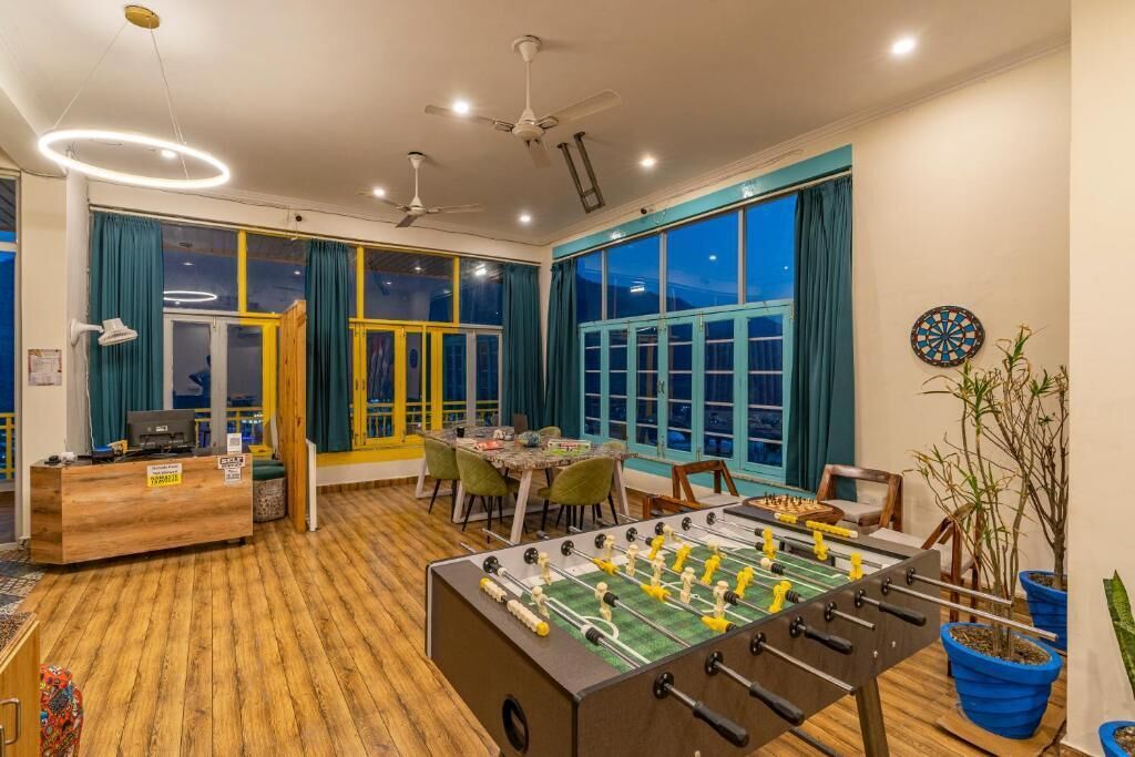 A room with a foosball table, a dartboard, and a table tennis table.