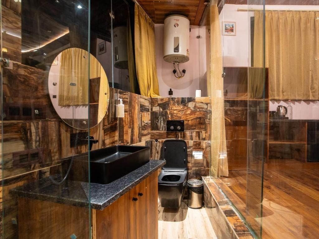 A bathroom with a wooden vanity, a toilet, a sink, and a shower area.