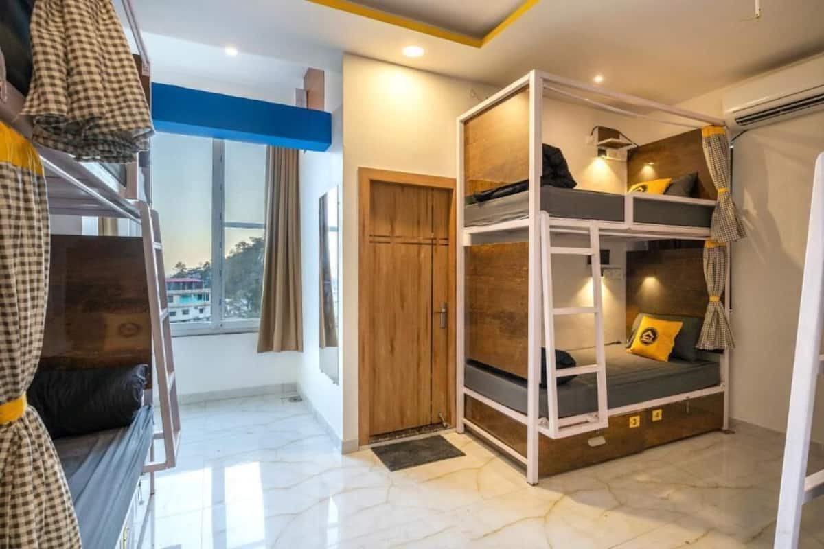 A bunk bed room with a wooden door, a window, and a view of buildings outside.