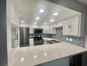 Uma cozinha moderna com armários brancos, eletrodomésticos de aço inoxidável e painel de azulejos.