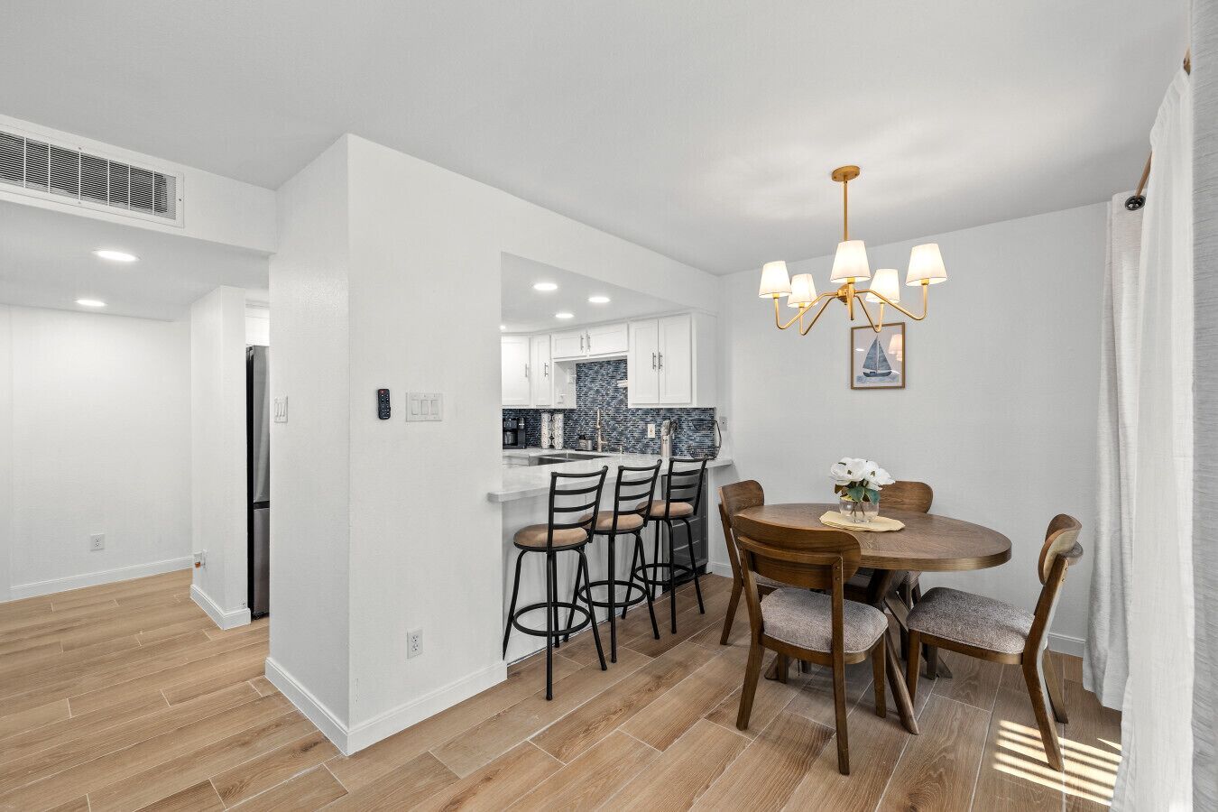 A modern kitchen with white cabinets, a black refrigerator, and a blue backsplash.