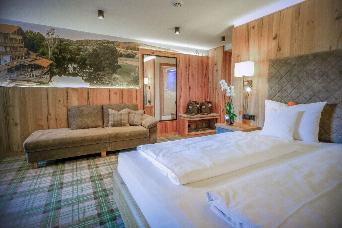 Et hyggeligt værelse med seng, sofa, lille bord og lampe.