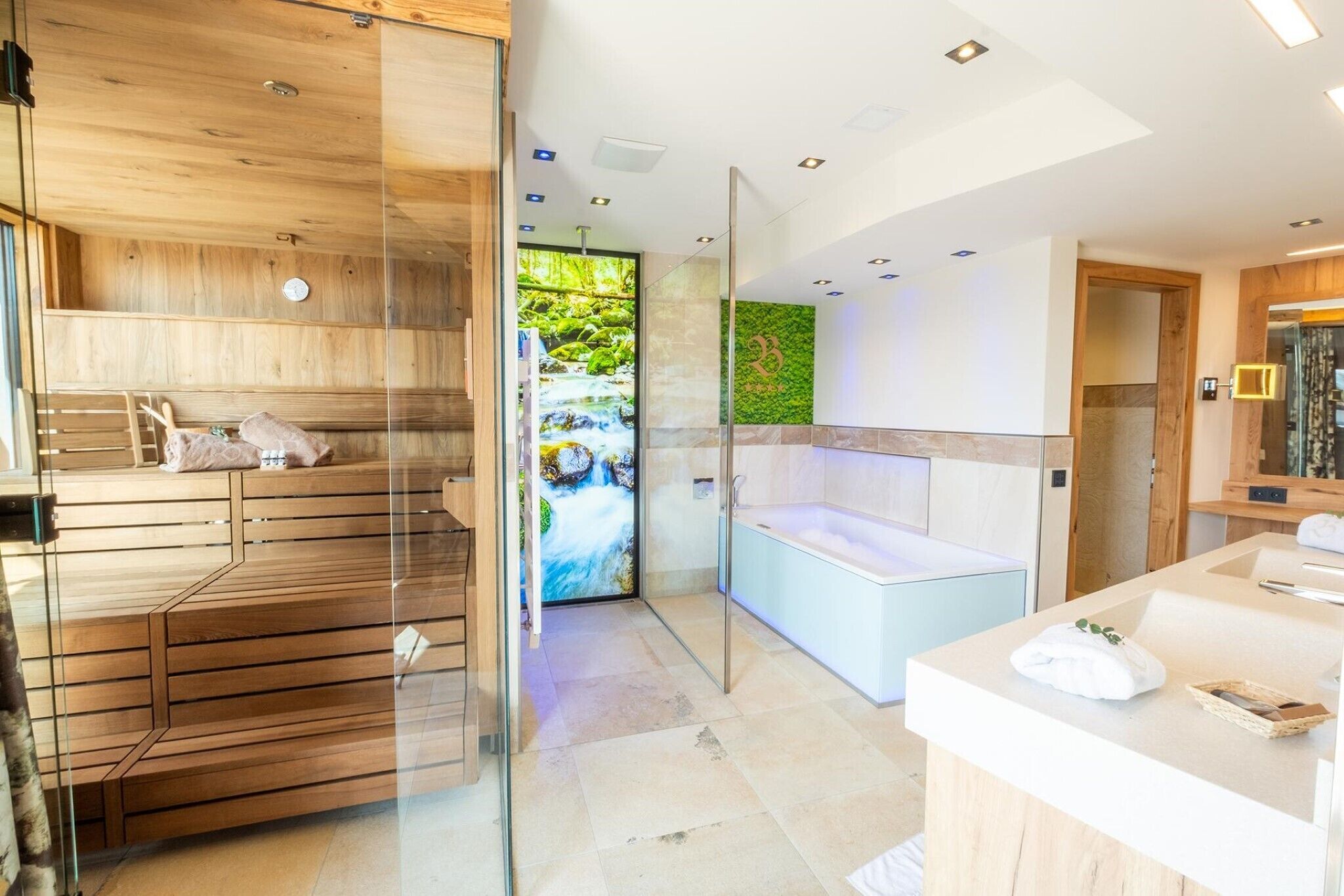 Un spa moderno con sauna de madera, una amplia pantalla digital mostrando una cascada y un área de bañera separada.