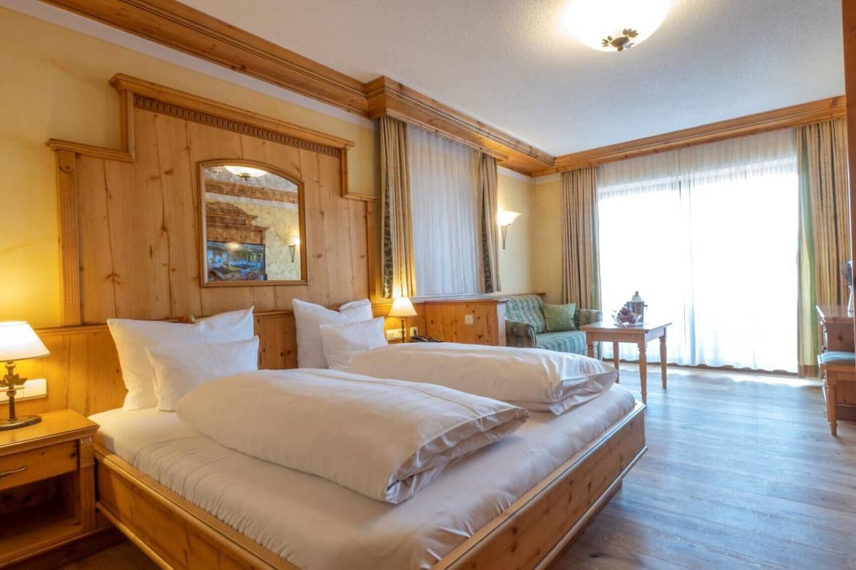 Et hotelværelse med dobbeltseng, et lille bord, en stol og udsigt til det fri.