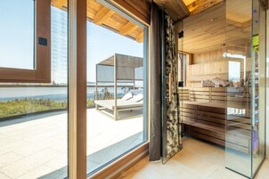 Una habitación moderna con un gran ventanal que da a un balcón, con cama y vistas al agua.