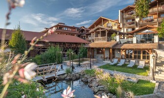 Un hotel de estilo chalete tradicional con arquitectura de madera, un pequeño estanque y zonas de estar al aire libre.