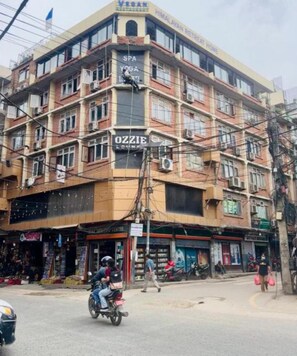A multi-story building with signage for a yoga center, a spa, and a vegan restaurant. - Quays Himalayan Hotel & Apartments  (Kathmandu)