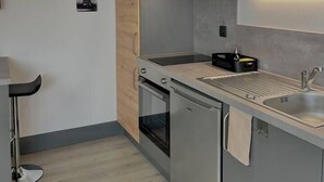 Uma cozinha moderna com armários de madeira, eletrodomésticos de aço inoxidável e uma luminária pendente.