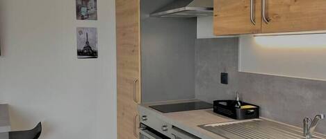 A modern kitchen with wooden cabinets, stainless steel appliances, and a pendant light.