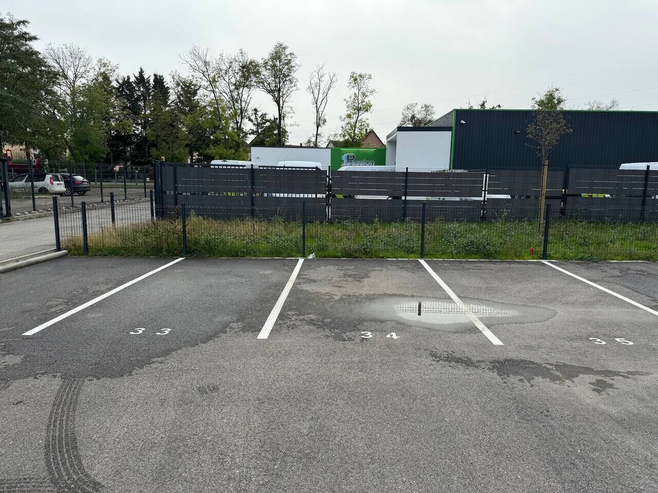 A parking lot with marked spaces and a fence.