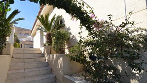 A set of stone steps leading up to a building with a white facade and a balcony.