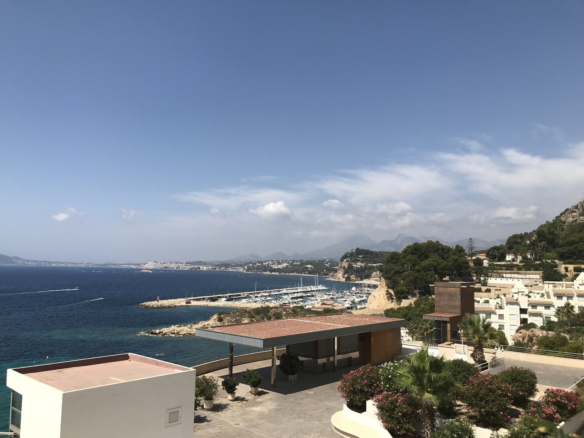 A coastal view with a marina, buildings, and a clear sky.