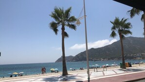 Una playa con palmeras, sombrillas y gente.